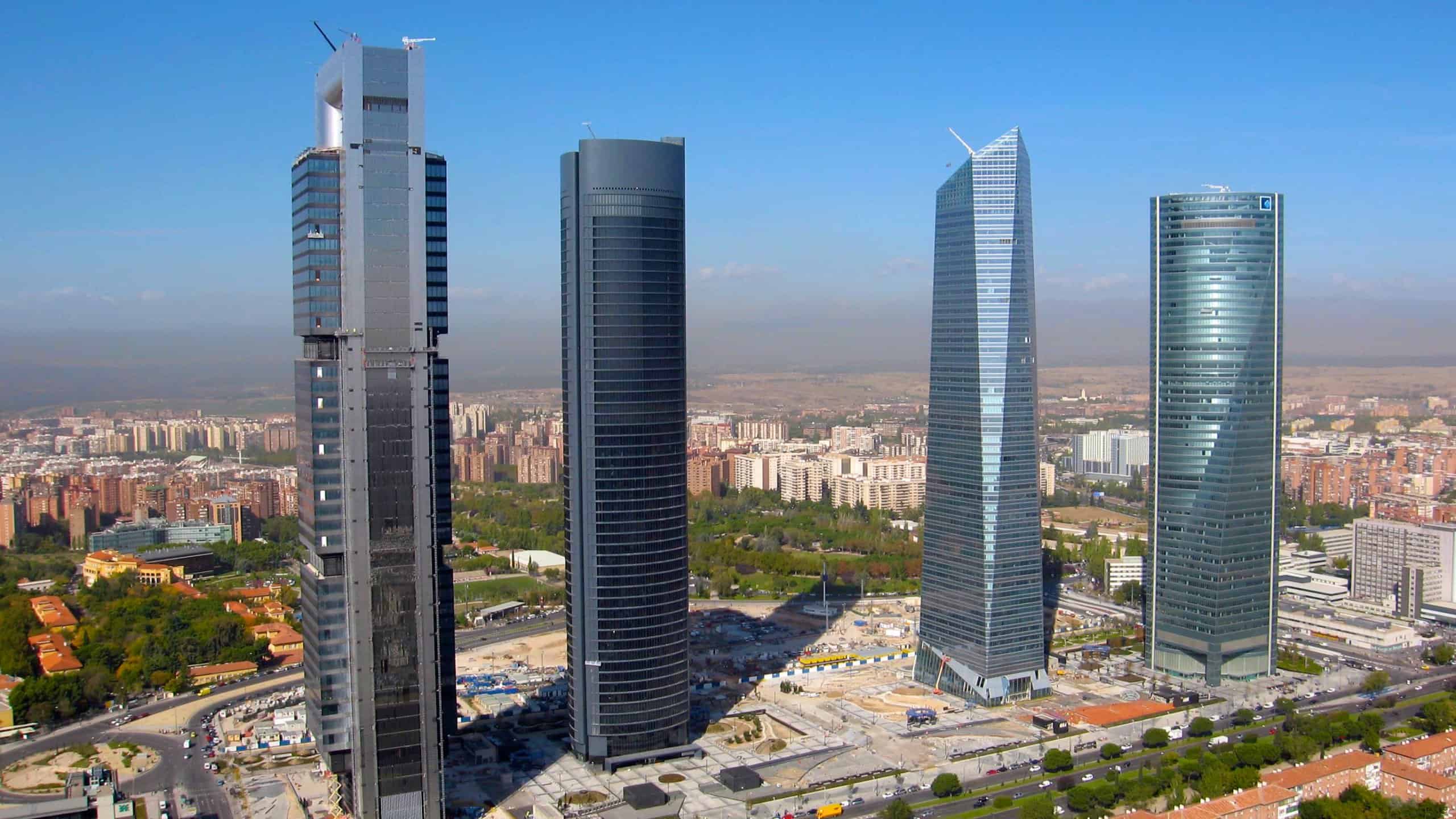 Cuatro Torres Business Area in Madrid featuring four modern skyscrapers against a clear blue sky.